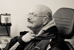 Man sitting a doctor's chair touching his neck